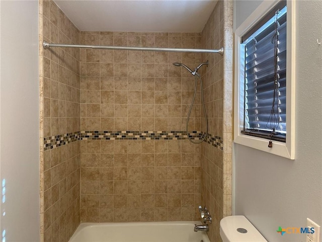 bathroom featuring tiled shower / bath combo and toilet