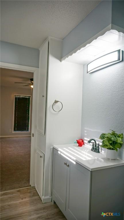 bathroom with ceiling fan, hardwood / wood-style floors, vanity, and a textured ceiling