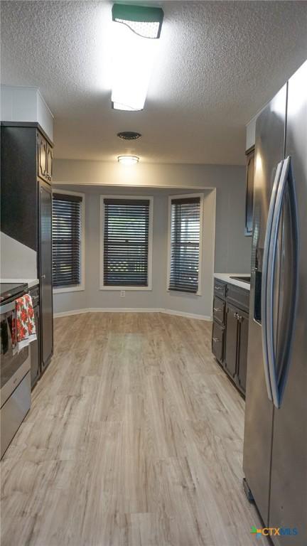 kitchen featuring a textured ceiling, dark brown cabinets, light hardwood / wood-style floors, and stainless steel appliances