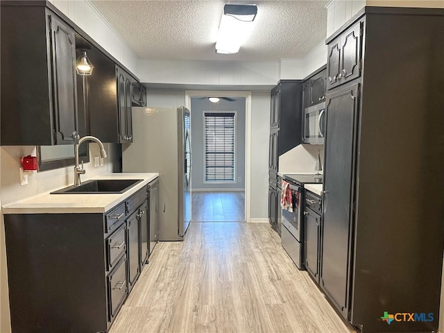 kitchen featuring a textured ceiling, light hardwood / wood-style floors, sink, and appliances with stainless steel finishes