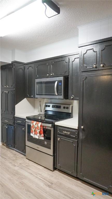 kitchen featuring a textured ceiling, light wood-type flooring, and stainless steel appliances