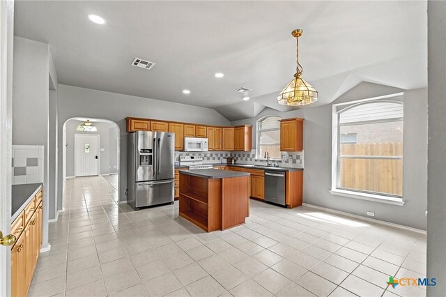 4504 Twin Oaks Cir, Killeen, TX 76542 - kitchen with appliances with stainless steel finishes, arched walkways, dark countertops, vaulted ceiling, and backsplash