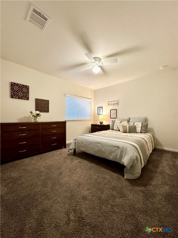 bedroom with a textured ceiling, dark carpet, and ceiling fan