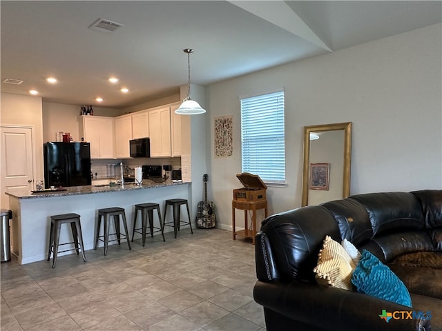 kitchen with white cabinets, kitchen peninsula, black appliances, decorative light fixtures, and dark stone countertops