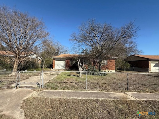 view of front facade with a garage, driveway, brick siding, and a fenced front yard