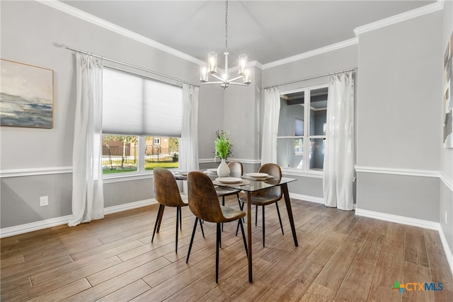 dining room with wood-type flooring, ornamental molding, and a notable chandelier