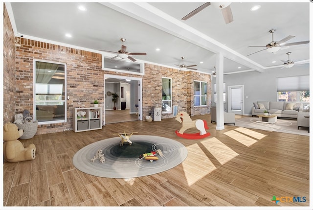 living room featuring beam ceiling, brick wall, and light hardwood / wood-style floors