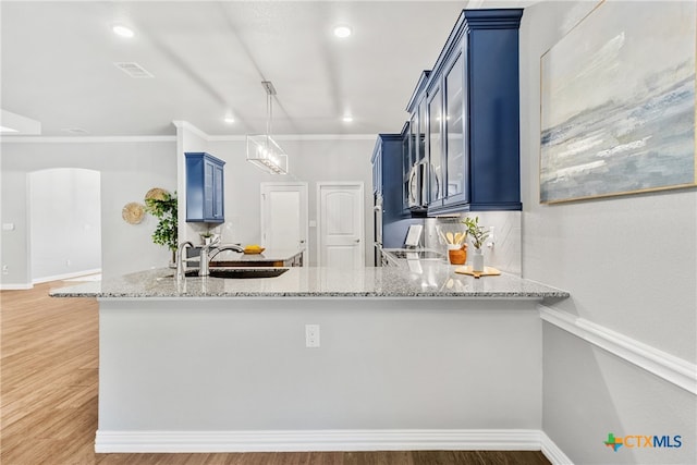 kitchen featuring blue cabinetry, light stone countertops, sink, kitchen peninsula, and wood-type flooring