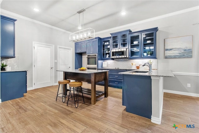 kitchen featuring light stone counters, sink, stainless steel appliances, and blue cabinets