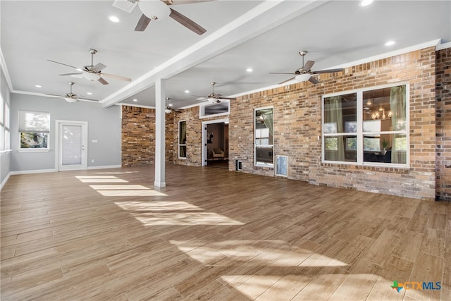 unfurnished living room featuring beam ceiling, crown molding, brick wall, and light wood-type flooring