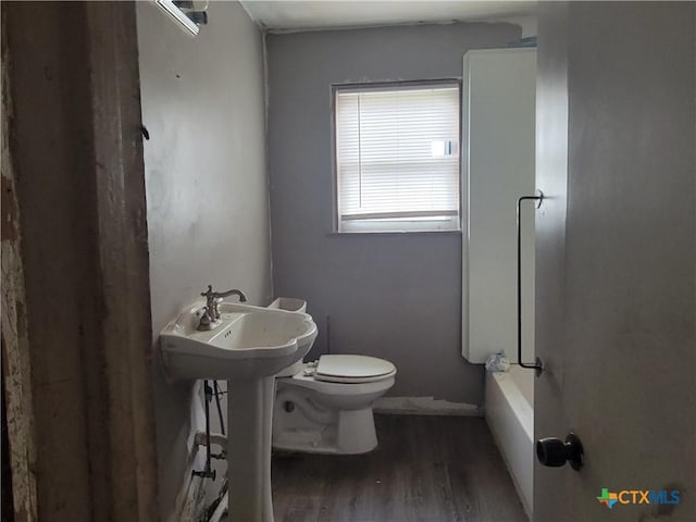 bathroom with wood-type flooring, toilet, and a bathing tub