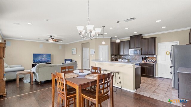 dining area with ornamental molding, hardwood / wood-style floors, and ceiling fan with notable chandelier