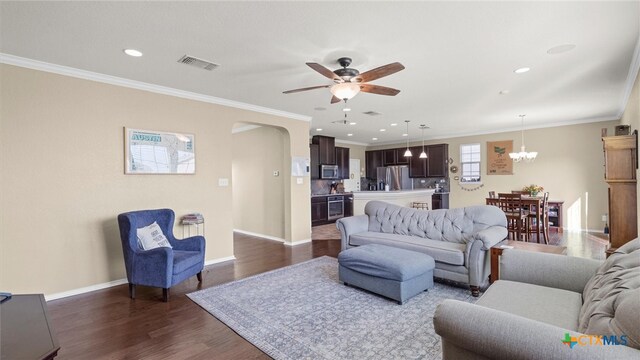 living room with ceiling fan with notable chandelier, dark hardwood / wood-style floors, and crown molding