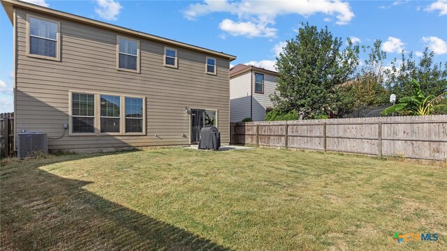 rear view of property with central AC unit and a yard