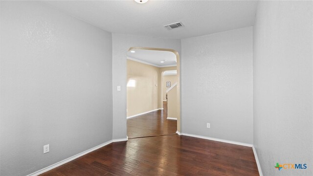 spare room featuring dark hardwood / wood-style floors and crown molding