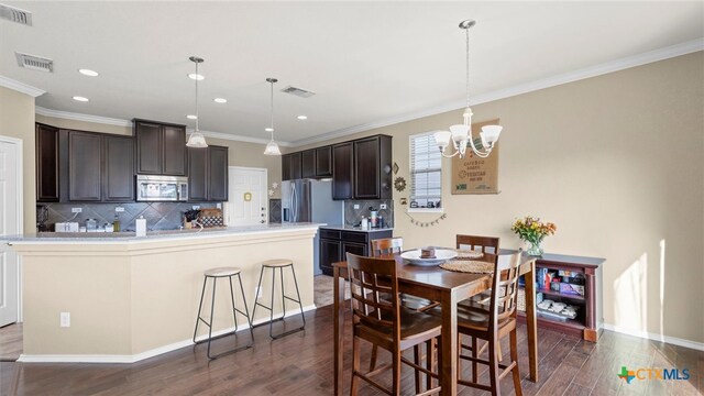 dining space with dark hardwood / wood-style floors, an inviting chandelier, and crown molding