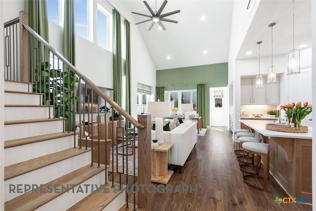 225 Dycus Bnd, Liberty Hill, TX 78642 - living area with high vaulted ceiling, healthy amount of natural light, a ceiling fan, dark wood-style floors, and stairs