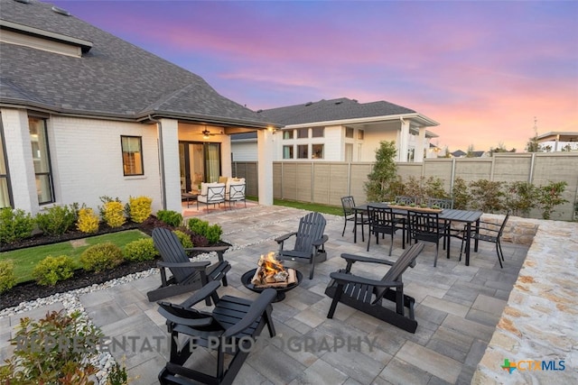 225 Dycus Bnd, Liberty Hill, TX 78642 - patio terrace at dusk featuring a fire pit, outdoor dining area, a fenced backyard, and a patio area