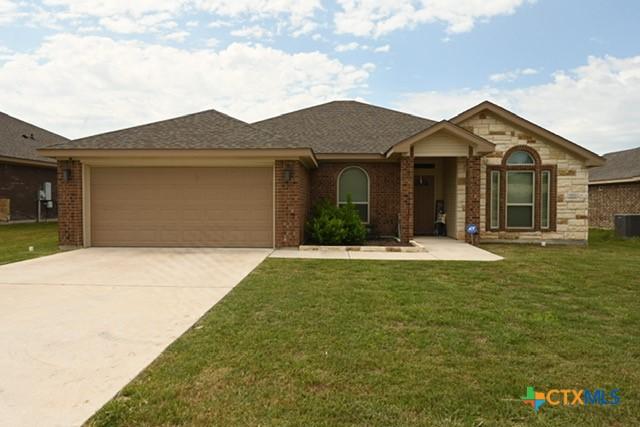 ranch-style house with a front lawn, driveway, brick siding, and a garage