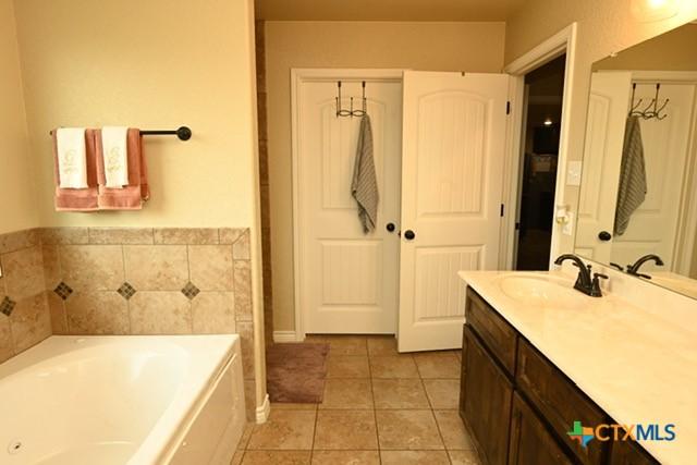 bathroom featuring tile patterned floors, vanity, and a garden tub