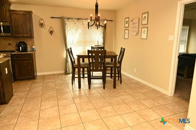 dining space featuring light tile patterned floors, baseboards, and a chandelier