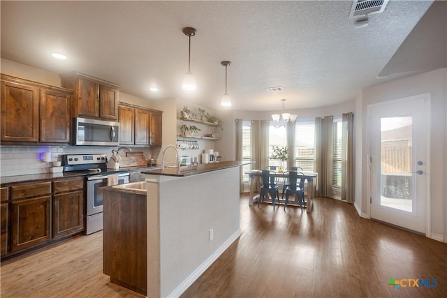 2520 Heartland Ave, Copperas Cove, TX 76522 - kitchen with stainless steel appliances, a chandelier, dark countertops, light wood finished floors, and a textured ceiling