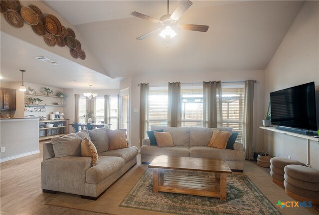 living room featuring light hardwood / wood-style floors, ceiling fan with notable chandelier, and high vaulted ceiling