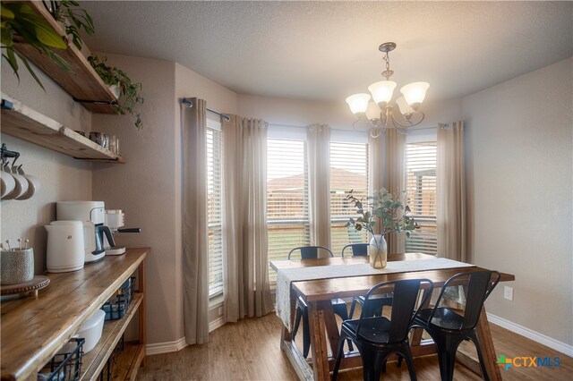 dining space featuring light hardwood / wood-style floors, a notable chandelier, and a textured ceiling