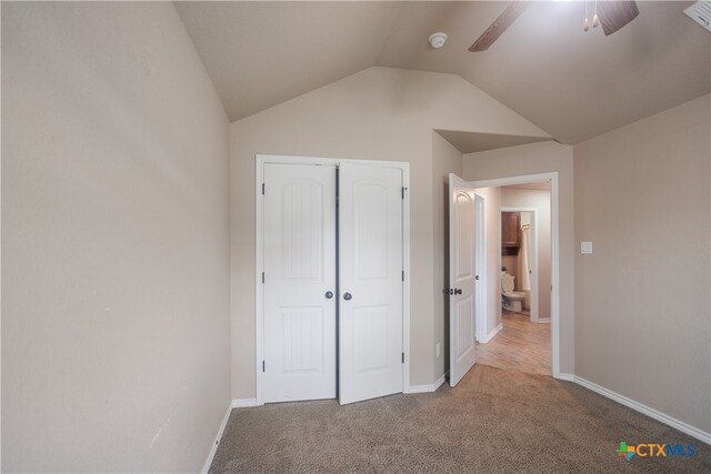 unfurnished bedroom with light carpet, ceiling fan, vaulted ceiling, and a closet