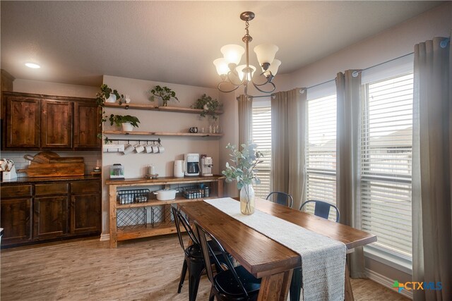 dining area featuring light wood-type flooring and a notable chandelier