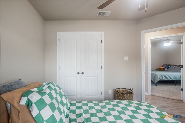 carpeted bedroom featuring ceiling fan and a closet