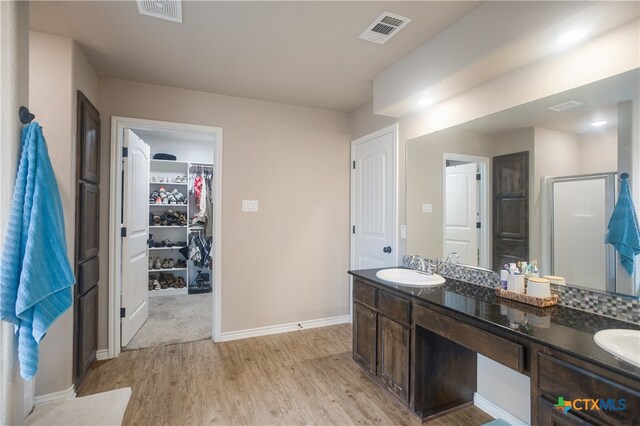 bathroom with hardwood / wood-style floors, vanity, and an enclosed shower