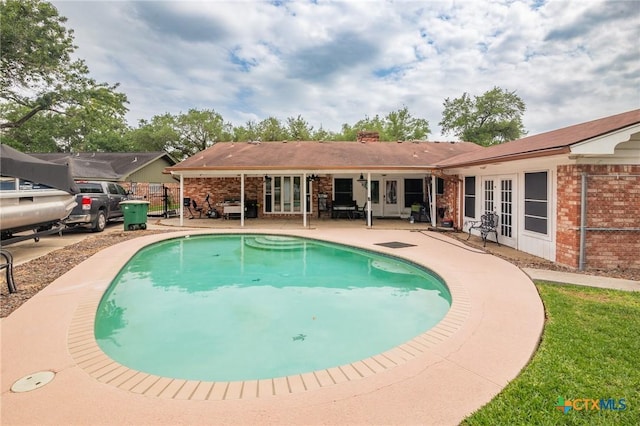 pool with a patio, fence, and french doors