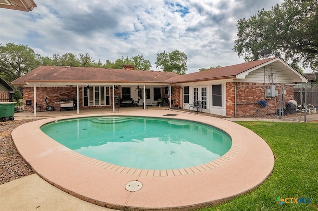 view of swimming pool featuring fence, a fenced in pool, french doors, a patio, and a yard