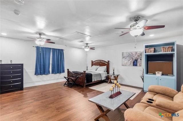 bedroom featuring ceiling fan, attic access, wood finished floors, and visible vents