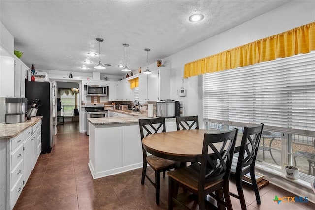 kitchen with dark tile patterned floors, stainless steel appliances, a peninsula, and white cabinetry