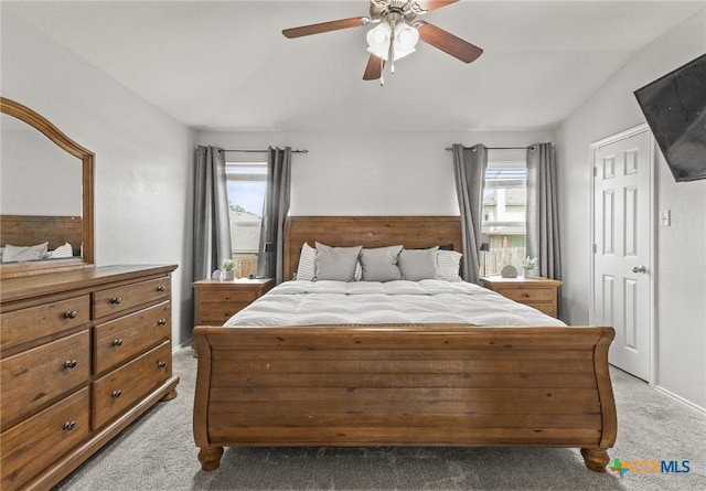 bedroom with a ceiling fan, light colored carpet, and multiple windows