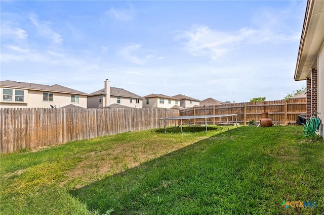 view of yard featuring a fenced backyard, a trampoline, and a residential view