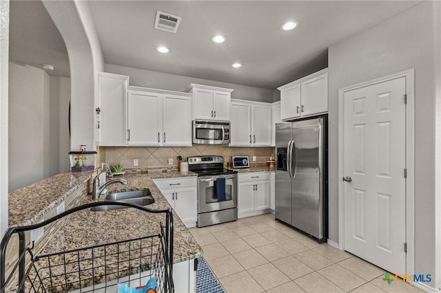 kitchen featuring visible vents, white cabinets, tasteful backsplash, light stone counters, and stainless steel appliances