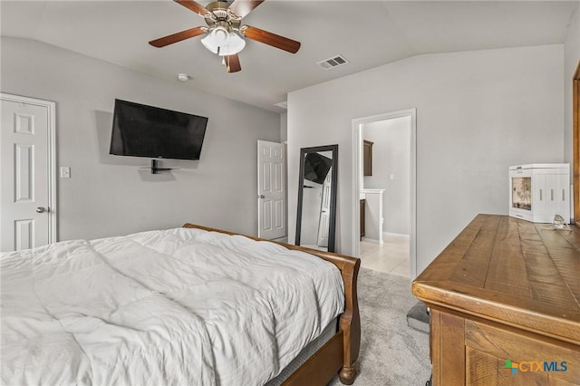 carpeted bedroom with ceiling fan, tile patterned flooring, visible vents, ensuite bathroom, and vaulted ceiling