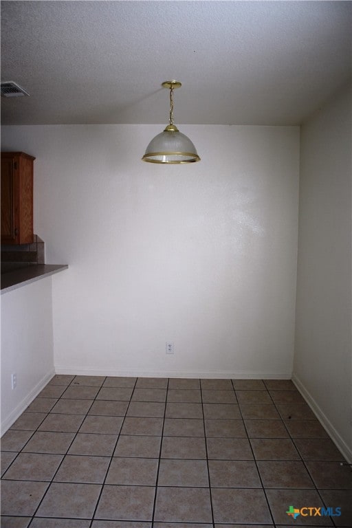 1402 Chips Dr, Killeen, TX 76549 - unfurnished dining area with light tile patterned floors, a textured ceiling, and baseboards