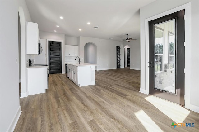 kitchen with a center island with sink, ceiling fan, white cabinets, and sink