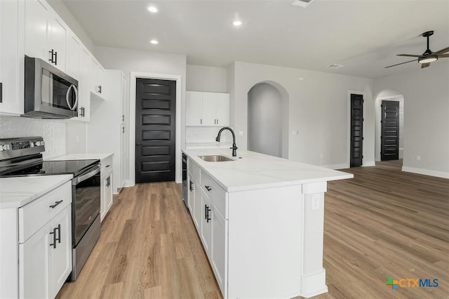 kitchen featuring decorative backsplash, stainless steel appliances, sink, white cabinetry, and an island with sink