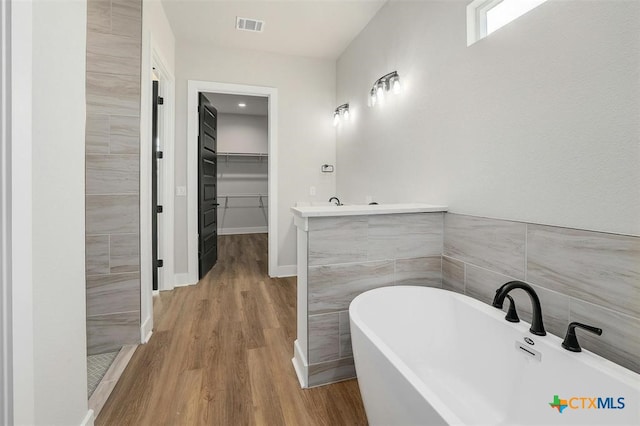 bathroom with a bathing tub, vanity, and wood-type flooring