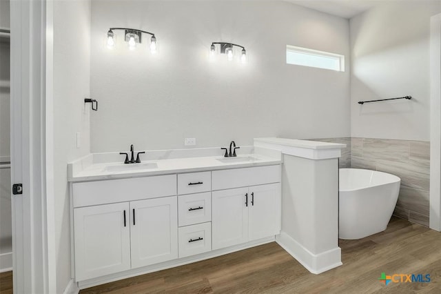 bathroom with hardwood / wood-style flooring, a washtub, tile walls, and vanity