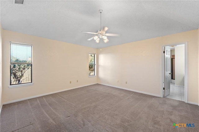 empty room with a textured ceiling, ceiling fan, a wealth of natural light, and carpet floors