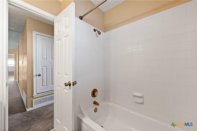 bathroom with tiled shower / bath combo and a textured ceiling