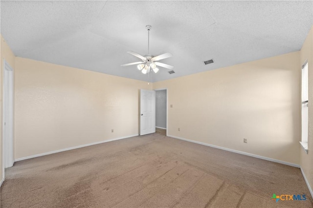 empty room featuring light carpet, ceiling fan, and a textured ceiling