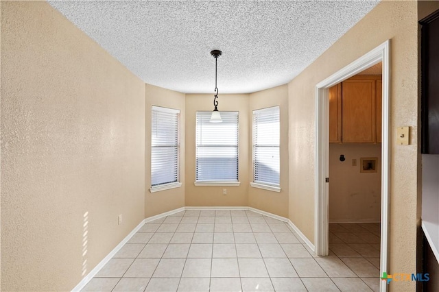 unfurnished dining area with a textured ceiling and light tile patterned flooring