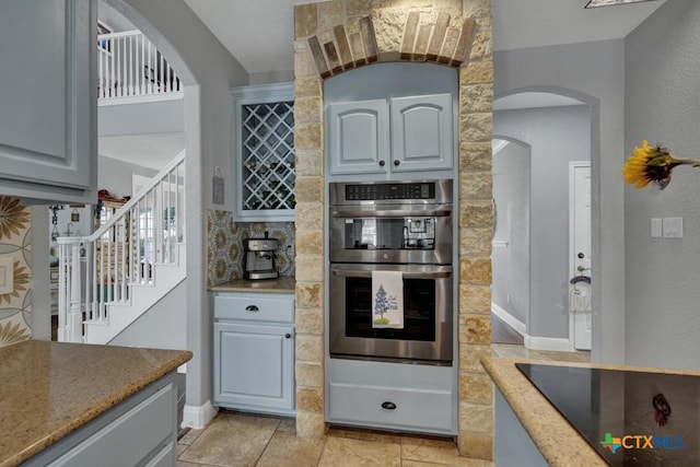 172 River Chase Dr, New Braunfels, TX 78132 - kitchen with black electric stovetop, stainless steel double oven, arched walkways, a textured wall, and baseboards